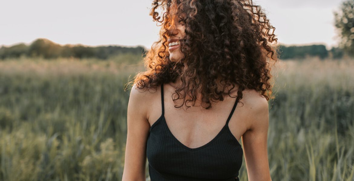 Woman with curly hair is smiling outside
