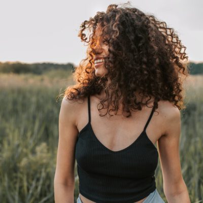 Woman with curly hair is smiling outside